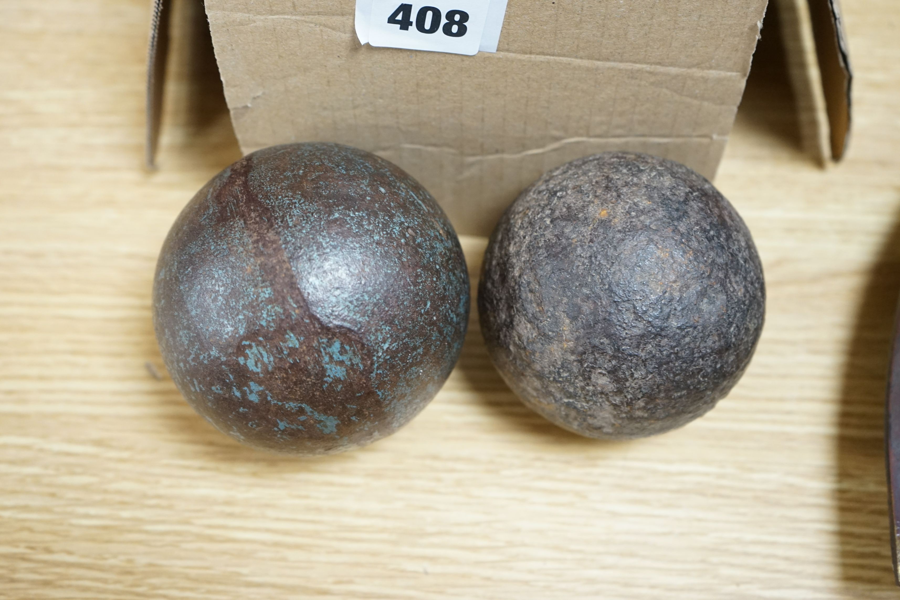 A collection of brass brewery bung collars and two cannon balls